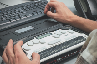 Man using screen reader next to computer keyboard